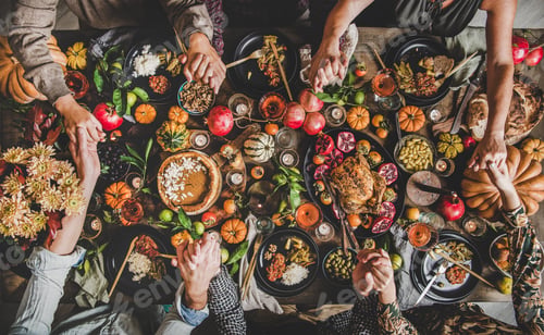 Preview: Family or friends praying holding hands at Thanksgiving celebration table