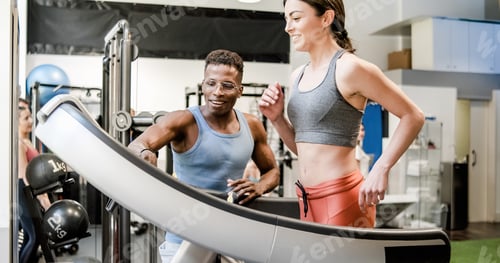 Preview: Black male instructor helping young woman running on treadmill
