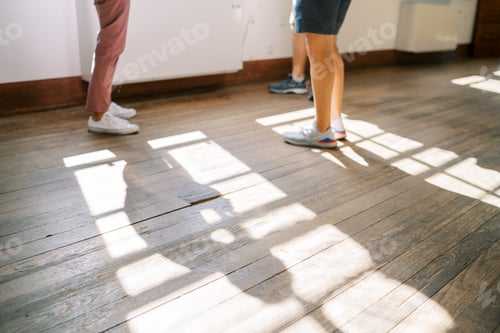 Preview: Men in sneakers stand on the wooden floor near the window. Cropped. Faceless