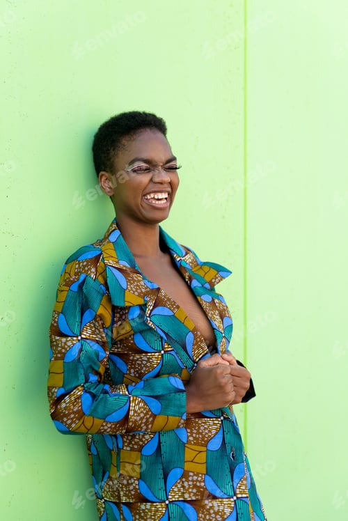 Preview: Black female in traditional African suit smiling against pistachio background