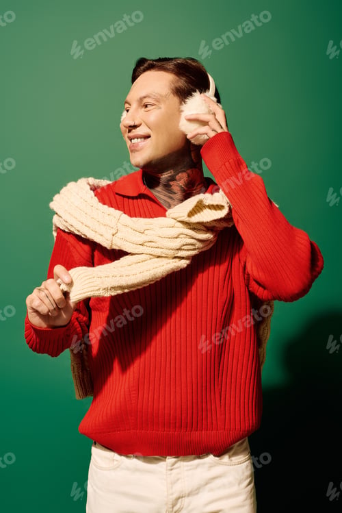 Preview: A young man with stylish tattoos playfully adjusts his earphones against a vibrant green backdrop