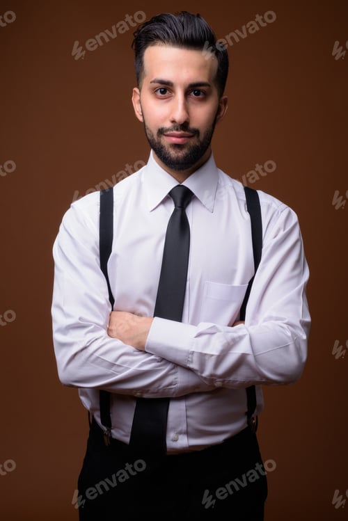 Preview: Young handsome bearded Iranian businessman against brown backgro