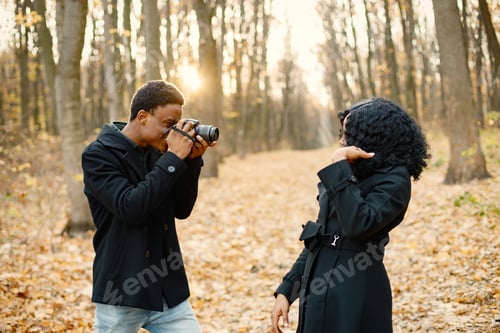 Vorschau: Schwarzer Mann macht ein Foto von einer schwarzen Frau im Herbstpark