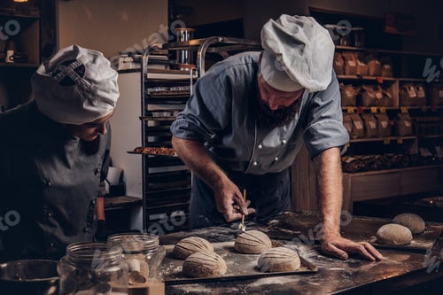 Preview: Chef teaching his assistant to bake the bread in a bakery.