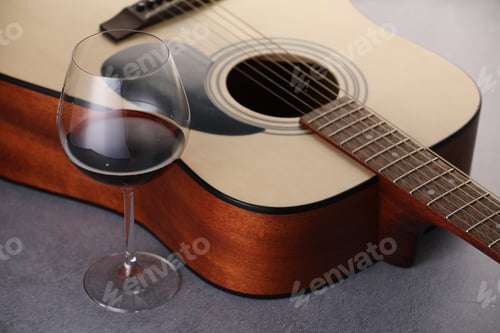 Preview: Acoustic guitar and red wine on grey table, closeup