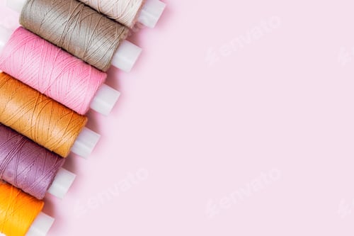 Preview: Tailor's work desk. Pattern of color sewing threads or reels on pink background