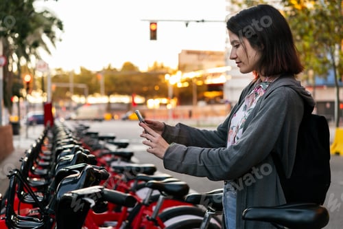 Preview: girl taking bike in public parking with a phone