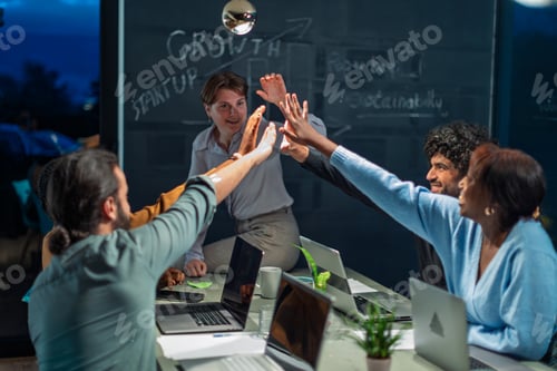 Preview: Startup team giving high five after achieving growth in office at night