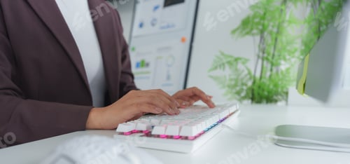 Preview: Businesswoman typing on keyboard in modern office with charts on screen