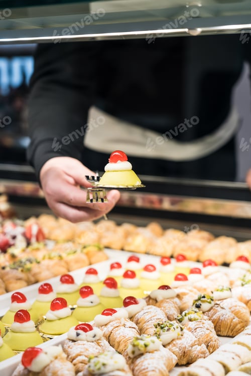 Preview: Unrecognizable baker picking up a traditional italian pastry at a coffee shop
