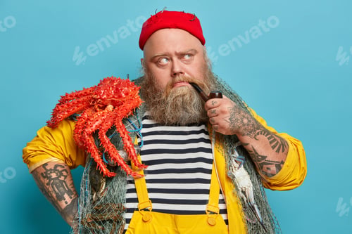 Preview: Handsome seaman with thick beard concentrated away thoughtfully smokes pipe dressed in sailor stripe