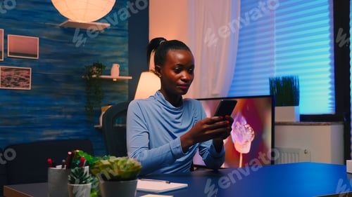 Preview: Black businesswoman browsing using smartphone sitting in living room