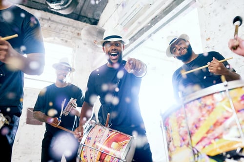 Preview: Low angle portrait of a group of handsome young male drummers playing at Carnival