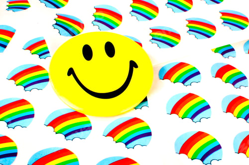 Preview: Closeup shot of a yellow smiley face on a rainbow wall background