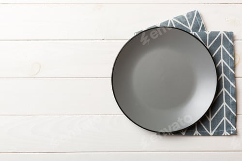 Preview: Top view on colored background empty round gray plate on tablecloth for food.
