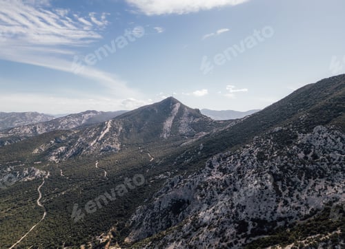 Preview: Scenic view of a mountain range with winding paths under a clear blue sky