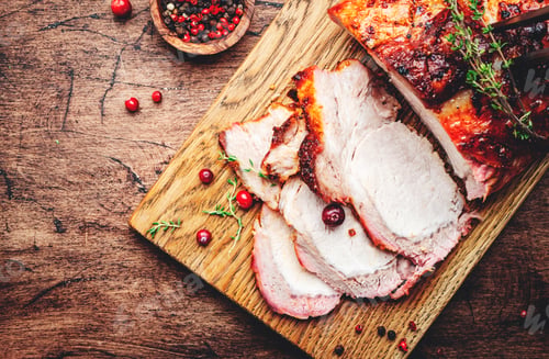 Preview: Baked pork loin, whole and cut meat pieces on rustic wooden cutting board with spices