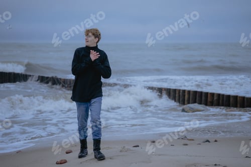 Preview: happy guy in a black sweater on the background of the sea looks to the side