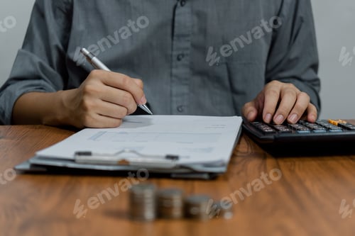 Preview: Man Writes on Documents with Calculator and Coins