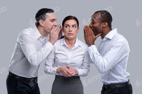 Preview: Gossiping. Beautiful Frightened Dark-Haired Young Woman Standing Between Two Men And Listening To