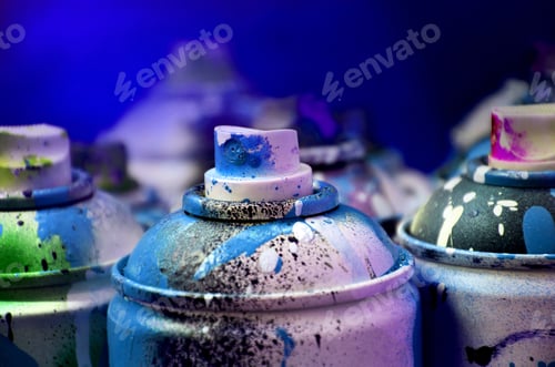 Preview: Still life with a large number of used colorful spray cans of aerosol paint lying on the treated