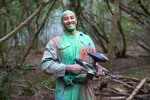 Preview: Paintball player in paintball wear marked with paint