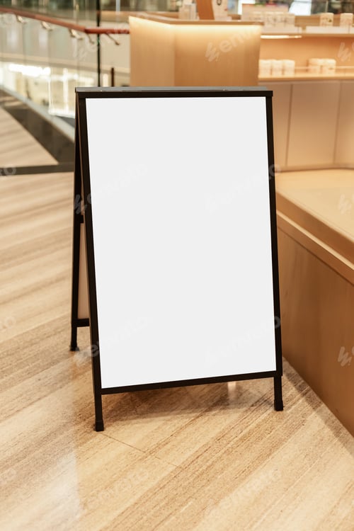 Preview: A black advertising stand with a blank surface is placed inside a shopping center