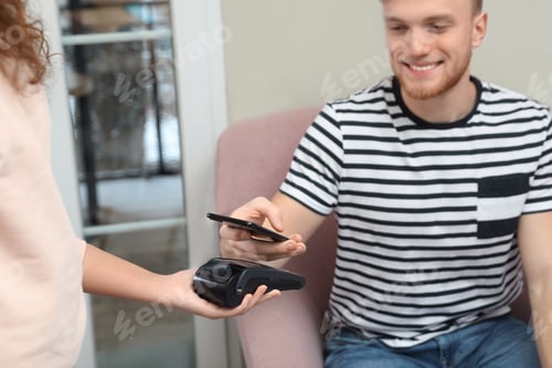 Preview: Client using smartphone and credit card machine for non cash payment in cafe