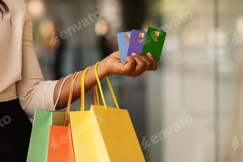 Preview: Unrecognizable black female holding three credit cards and shopping bags