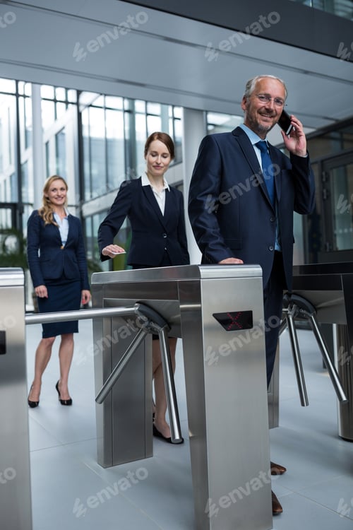 Preview: Businesspeople scanning their cards at turnstile gate