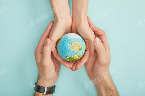 Preview: top view of man and woman holding planet model on turquoise background, earth day concept