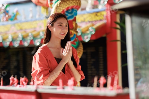 Preview: Young asian woman showing respect at a chinese temple