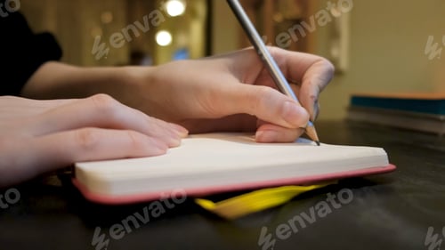 Preview: Close-up of woman writing something in notebook in cafe. Concept. Woman writes down something