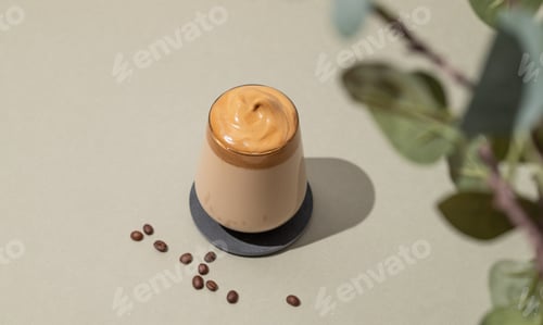 Preview: Dalgona coffee. Whipped instant vegan coffee in a glass with beans and shadow leaves