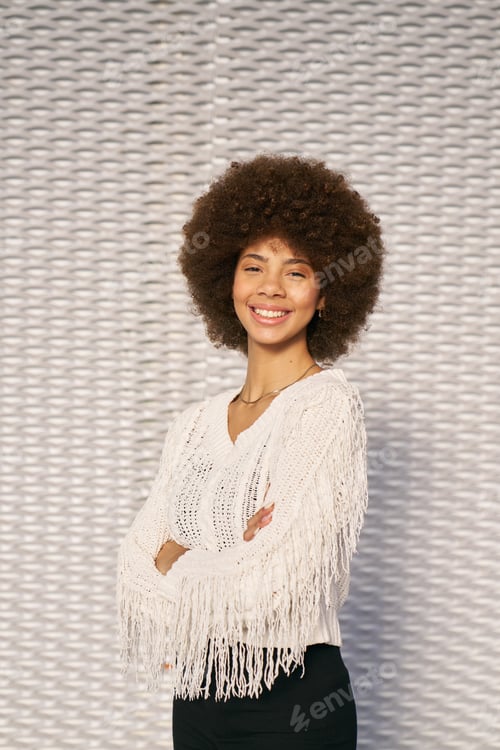 Preview: A woman with curly hair is wearing a white sweater with fringe
