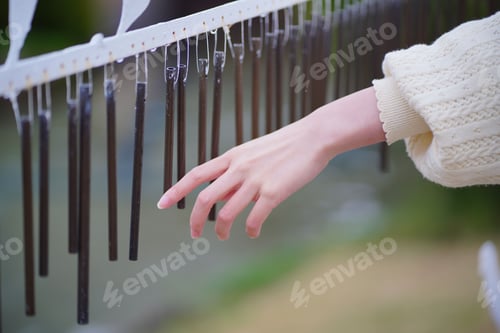 Preview: Closeup shot of a woman's hand touching brown wind chimes