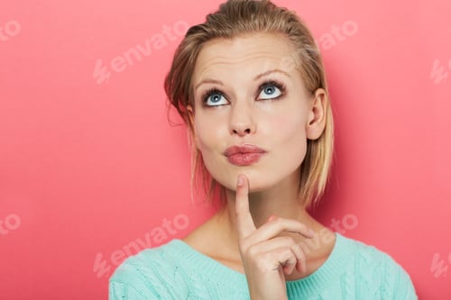 Preview: Hard choice. A beautiful young woman thinking to herself while isolated on pink.