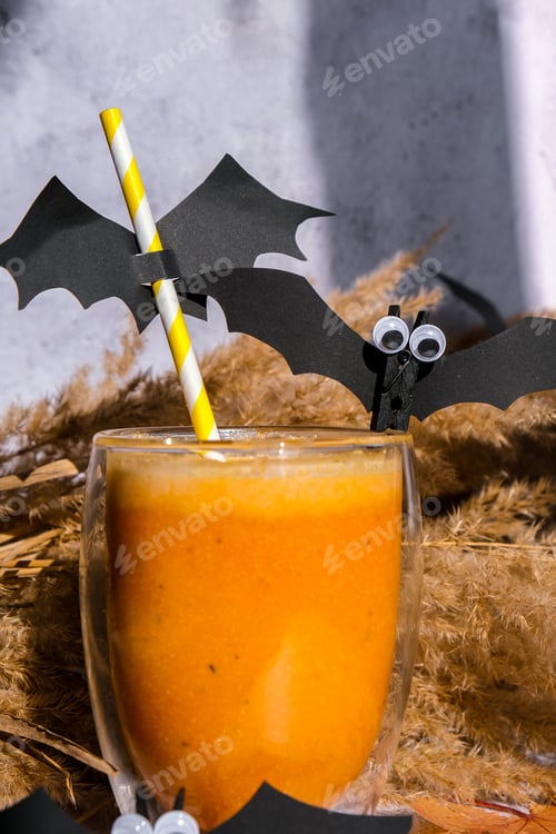 Preview: Pumpkin smoothie spiced latte. Fall Drinks for Halloween decorations with bat on straw. Holiday drin