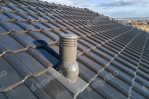 Preview: Closeup of ventilation pipe on house roof top covered with ceramic shingles. Tiled covering of