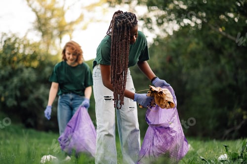 Preview: Two young women volunteers picking up trash in park