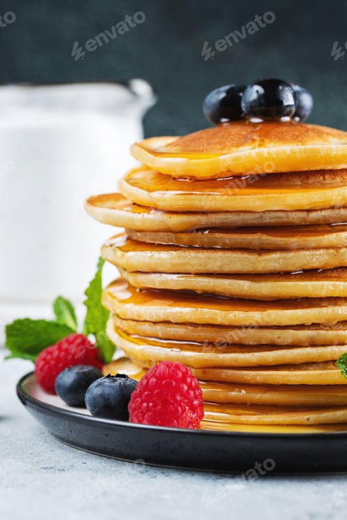 Vista previa: Delicious pancakes, with fresh blueberries, raspberry and maple syrup or honey on a dark background