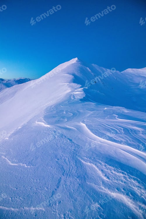 Preview: Vertical shot of mountains covered in snow under a bright sky