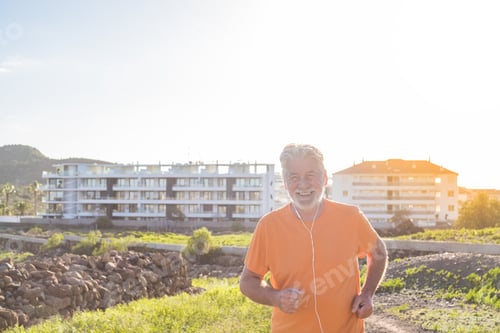Preview: old man or senior running alone in a rural zone around the nature and houses - one mature