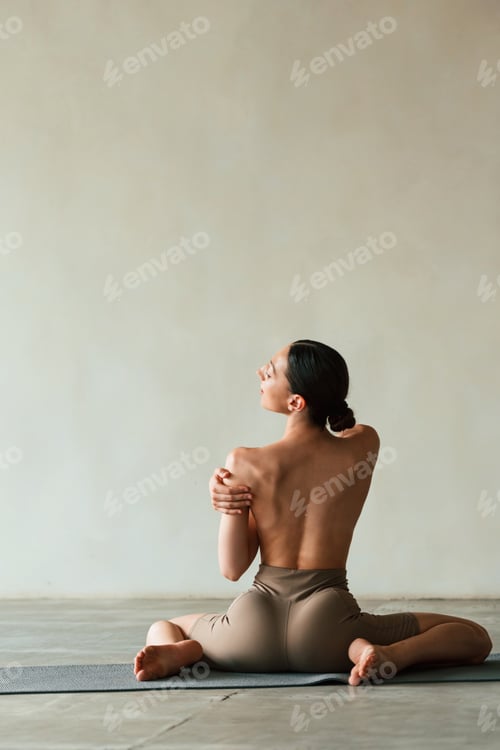 Preview: sitting, rear view. Young woman with slim body type is in fitness clothes in the studio