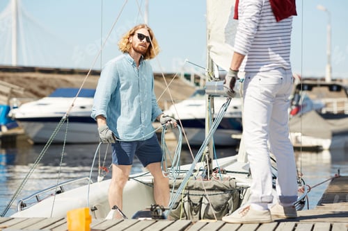 Preview: Young man fixing rope on sail boat