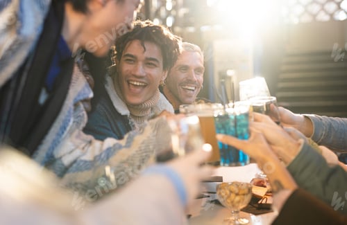Preview: A group of grinning friends gather around a bar table