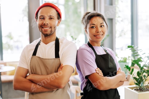 Preview: Two confident baristas smiling with arms crossed in coffee shop