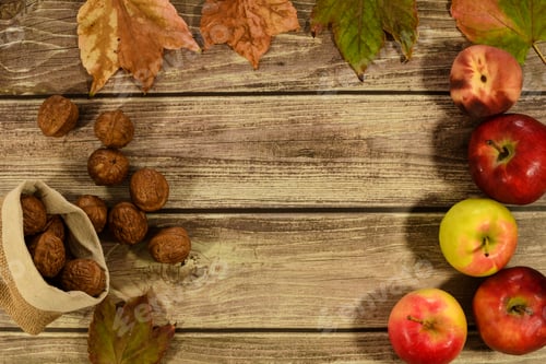 Preview: Leaves, apples, a peach and nuts on a wooden table with a space for a text