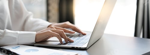 Preview: Asian businesswoman sitting in an office looking with graph detail on laptop computer Chart of real