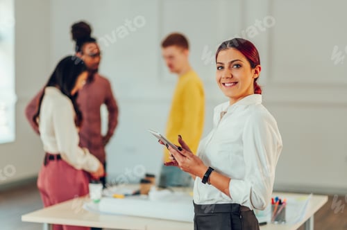 Preview: Portrait of a woman architect posing in the office during a meeting and using a tablet